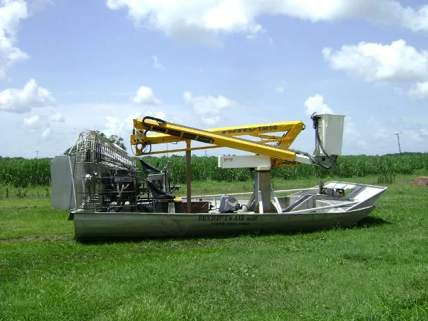 Custom airboat with articulated boom folded above its work platform