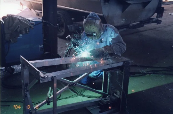 Welder fabricating an aluminum equipment frame in the Faucheux shop